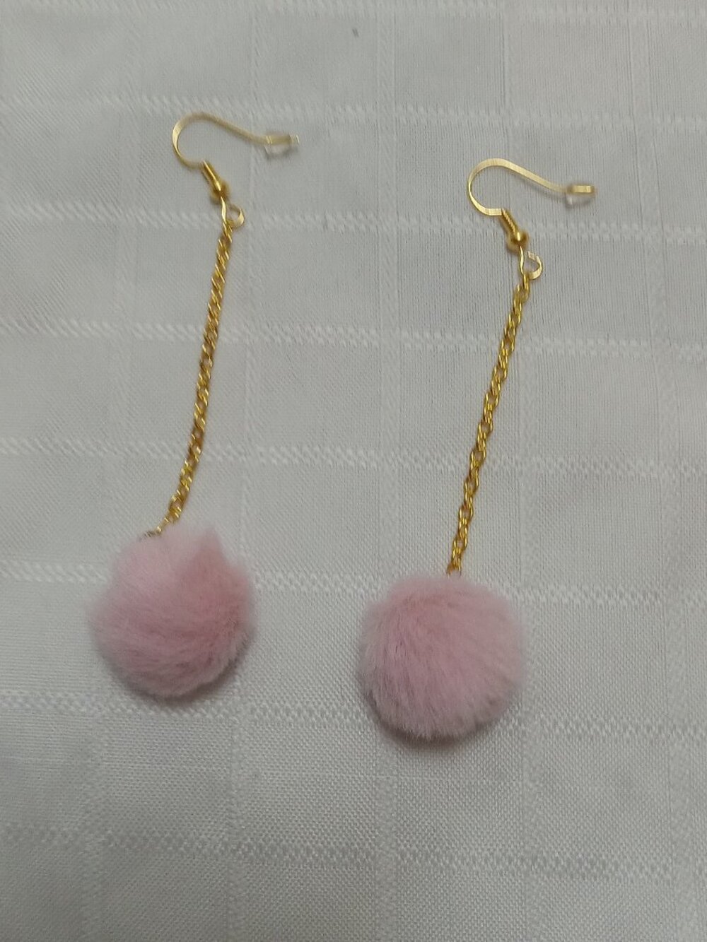 Handmade earrings with small pom-poms and gold-colored accent hooks and chains